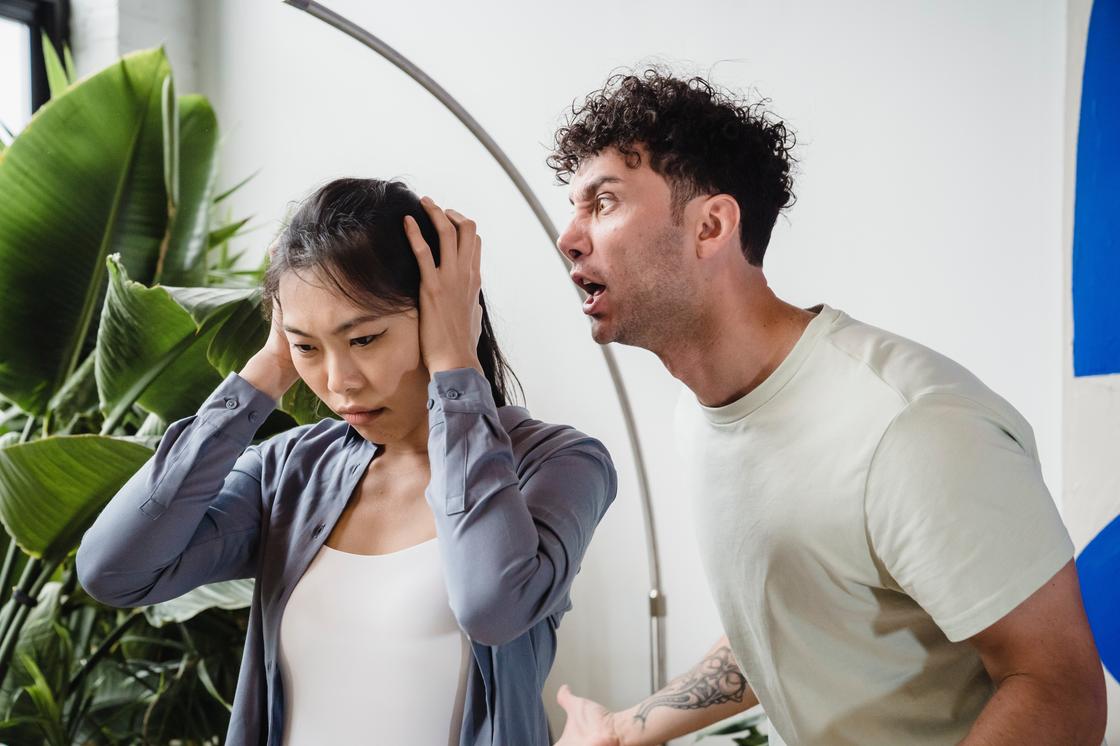 Чоловік кричить на жінку, яка закриває вуха руками Мужчина кричит на женщину, которая закрывает уши руками