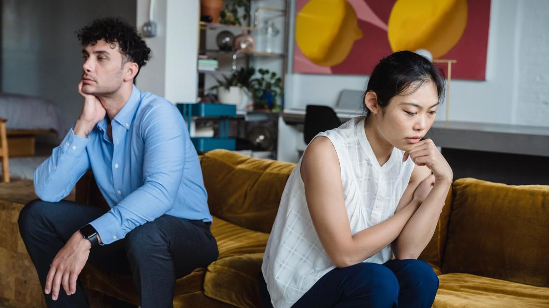 Чоловік і жінка сидять на дивані в задумливі пози. Мужчина и женщина сидят на диване в задумчивых позах