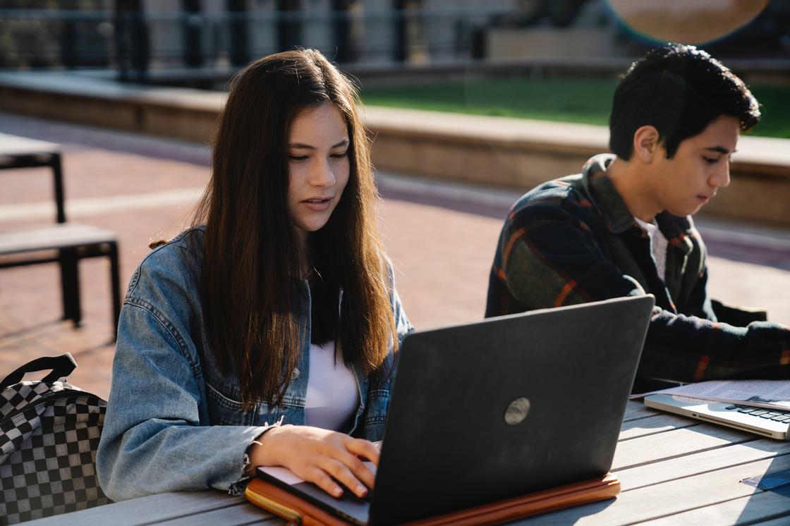 Дівчина з ноутбуком сидить поруч із хлопцем Девушка с ноутбуком сидит рядом с парнем