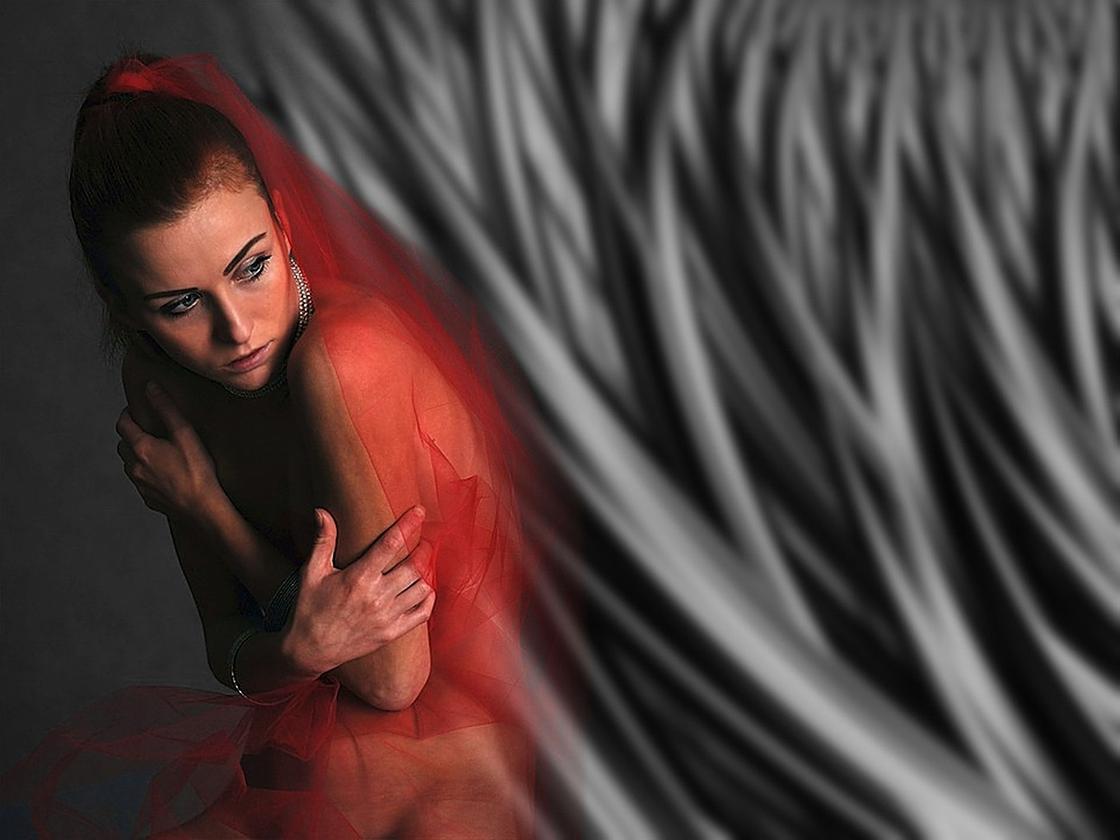 Дівчина обіймає себе руками під червоною шаллю Девушка обнимает себя руками под красной шалью