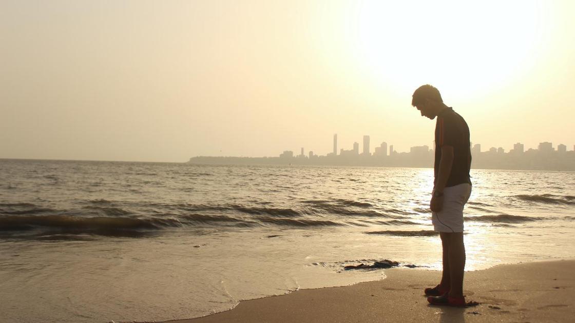 Самотній чоловік стоїть на березі моря Одинокий мужчина стоит на берегу моря